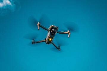 Drone flying overhead in cloudy blue sky