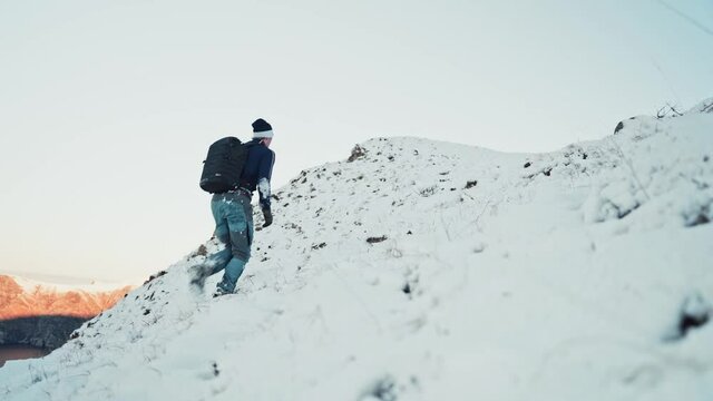 Young man hiking uphill on a snow-covered mountain in Hoddevik, Norway.