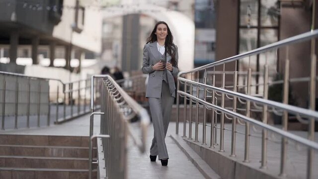 Stylish young woman in a business suit threesome walking the city model gait