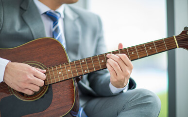 Fototapeta na wymiar Crop photo businessman wearing suit relaxing by playing guitar feel casual and relaxation in work office