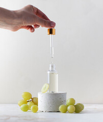 Female hand dripping natural grape seed oil into glass bottle