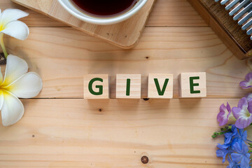 Positive Words Vocabulary  concept, GIVE word cube wooden with Coffee mugs, Kalimba and small flowers on the wooden background, start your work day refreshed.