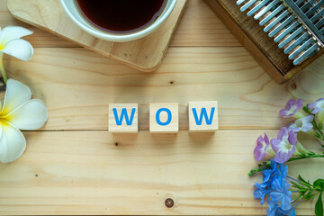 Positive Words Vocabulary  concept, WOW word cube wooden with Coffee mugs, Kalimba and small flowers on the wooden background, start your work day refreshed.