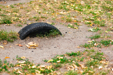 Old half car tire buried with grass on the ground