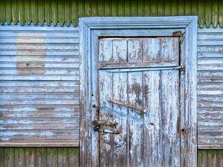 closed door with padlock on blue painted weathered wooden barn wall