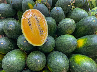 Pile of oval shaped yellow watermelon at fruit market 