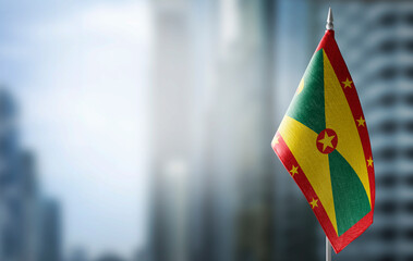 A small flag of Grenada on the background of a blurred background - obrazy, fototapety, plakaty