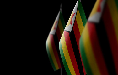 Small national flags of the Zimbabwe on a black background - obrazy, fototapety, plakaty