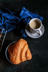 Croissant with coffee on dark background. Perfect breakfast in the morning.