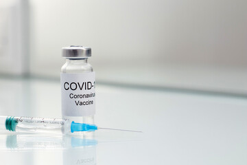Vial tube with coronavirus vaccine for 2019-nCoV COVID-19 virus and syringe on glass background