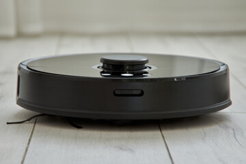 Black robot vacuum Cleaner effectively cleans the floor in automatic mode. Smart Home technology