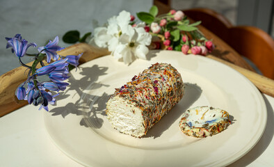 A plate with fresh french goat cheese with honey and flowers and spring flowers on the tray