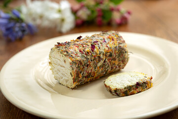 A plate with fresh french goat cheese with honey and flowers and spring flowers on the wooden table
