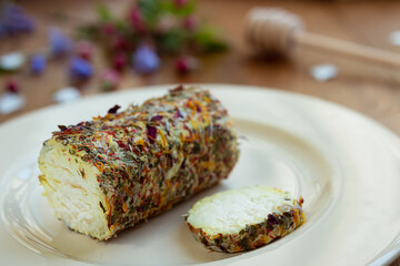 Goat cheese with honey and flowers on the light plate on the wooden table