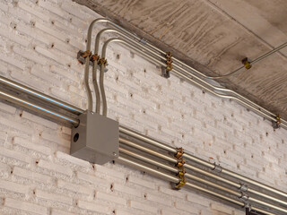 the installation of a electric wire system in the building on white brick wall, electrical conduit...