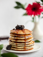 A stack of pancakes with jam from cones on a light background