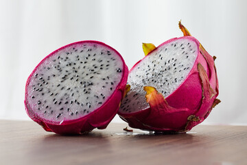 Dragon fruit sliced into 2 pieces on a wooden table.