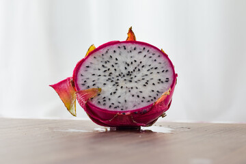 A slice of dragon fruit facing forward on a wooden table.