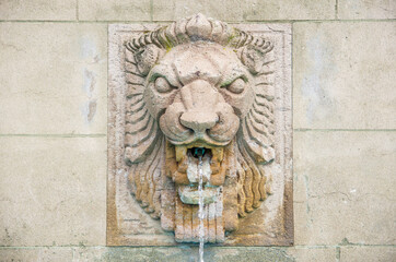 Lion head fountain on concrete wall.