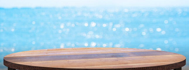 Empty round wood table with summer blue sea blur background.copy space for display of product on online media