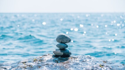 Pyramid stones on the seashore on a sunny day on the blue sea background. Happy holidays. Pebble beach, calm sea, travel destination. Concept of happy vacation on the sea, meditation, spa, calmness.