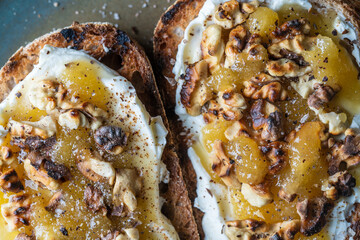 Two bread toast with cream cheese, roasted walnuts, honey, pepper and salt, close up, top view