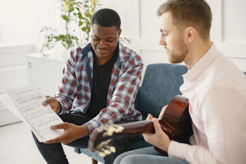 African man and Caucasian man playing guitar