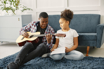 African father teaches his daughter to play guitar