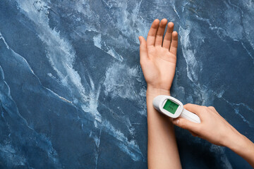 Female hands with infrared thermometer on color background