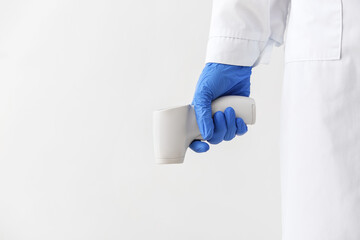 Doctor with infrared thermometer on white background, closeup