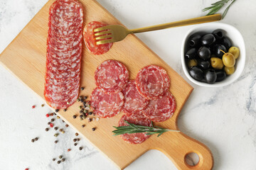 Board with tasty salami on light background