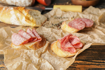 Tasty sandwiches with salami on wooden background