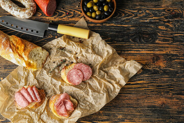 Tasty sandwiches with salami on wooden background