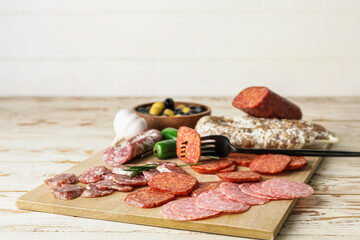 Board with slices of different sausages on table