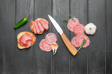 Composition with slices of salami on dark wooden background