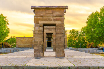 Fototapeta na wymiar Fotografía frontal del Templo de Debod durante el atardecer con un cielo naranja.