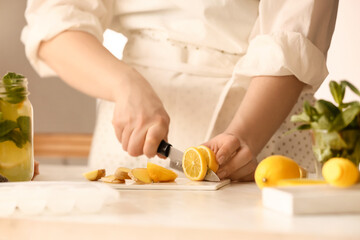 Obraz na płótnie Canvas Woman preparing ginger lemonade in kitchen