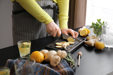Woman preparing ginger lemonade in kitchen