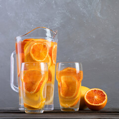 Refreshing orange lemonade on grey wooden table. Summer drinks concept.
