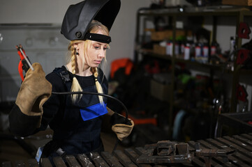 Attractive girl in workshop with instrument in hand and protective mask on face