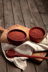Red quinoa seeds on wooden background. Healthy vegan food concept.