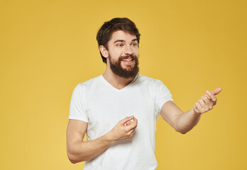 A man with a bushy beard on a yellow background gestures with his hands