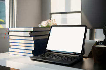 Mock up digital tablet with wireless keyboard and books on white office desk.