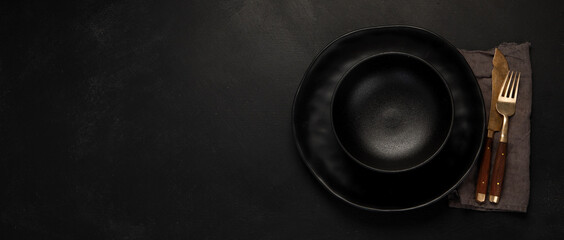 Table setting with a black plates on a black background. Minimalism concept.