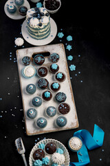 Delicious cake and cupcakes in blue on dark background. Table setting for celebration.