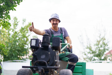 Satisfied farmer portrait sitting behind the wheel of a two-wheeled tractor.