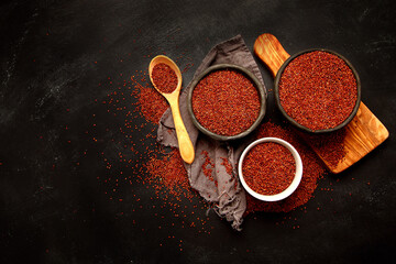 Red quinoa seeds on dark background. Healthy vegan food concept.