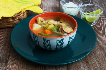 Plato de sopa de pollo con verduras sobre mesa de madera. Comida saludable hecha en casa.