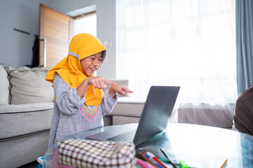 excited young muslim kid while studying online from home using laptop