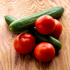 two cucumbers and four tomatoes on a wooden background